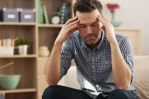 Træt mand med hænder ved tindingerne' title='Dårlig fysisk modstand og depression