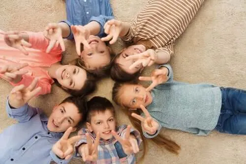 Bambini che giocano per terra in cerchio.' title='Insegnare ai bambini a condividere